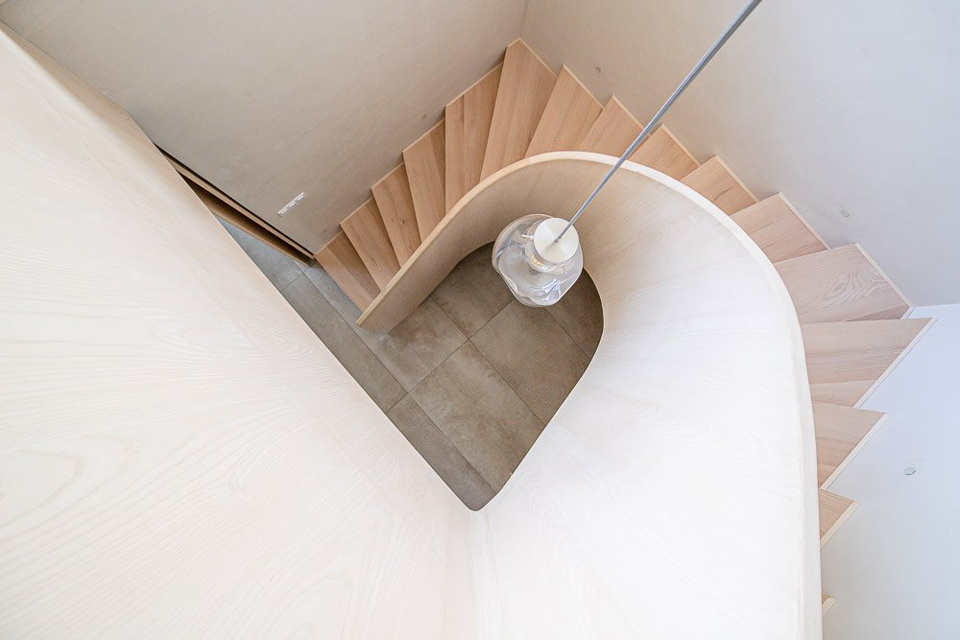 INTERIÉR DŘEVĚNÉ ZATOČENÉ SCHODIŠTĚ PLNÉ ZÁBRADLÍ KŘIŠŤÁLOVÉ SVÍTIDLO BOMMA 